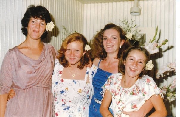 Anne as a teenager in a floral dress with family at a celebration